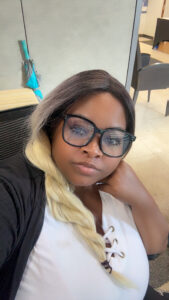 Carmen Woodson, staff member at Magdala, smiling in a selfie wearing glasses and a white top.