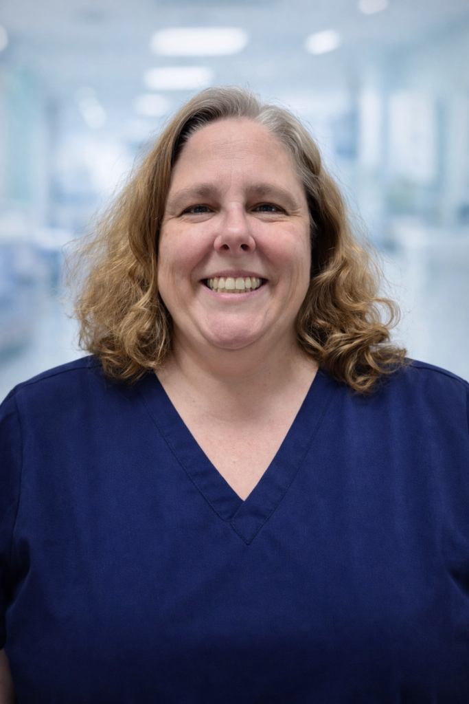 Julie Rojano, RN, smiling in navy scrubs against a soft medical background