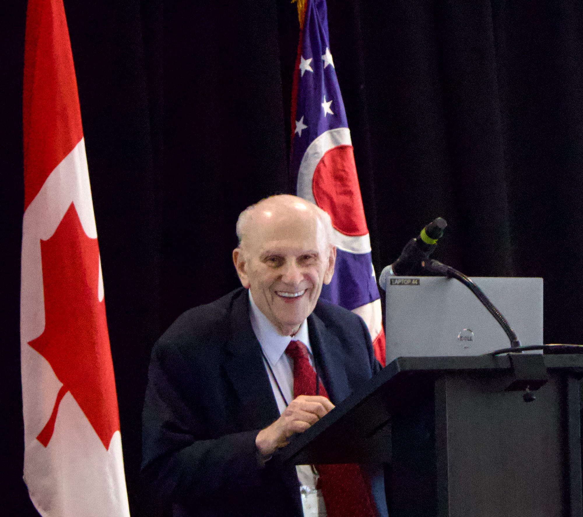 Thomas J. Mangogna smiling at a podium during the 2026 International Community Justice Association conference.